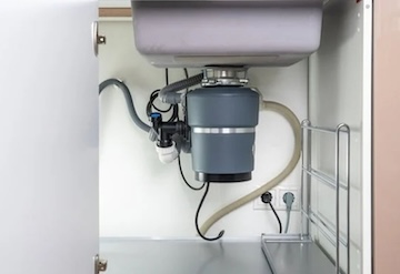 A garbage disposal under a sink recently repaired for a client.